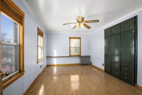 a view of empty room with wooden floor and fan