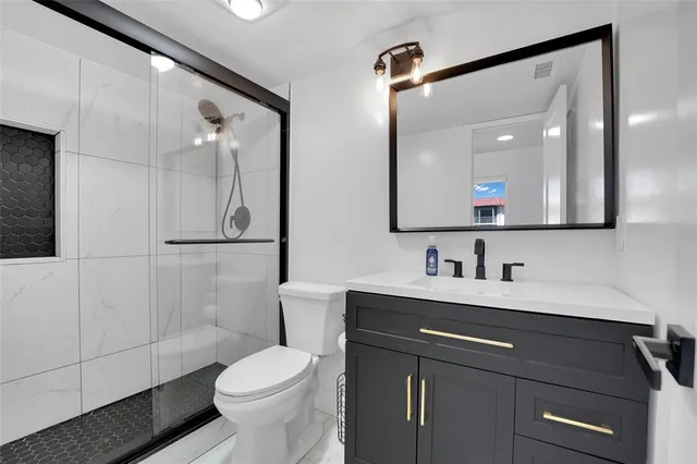 a bathroom with a sink a toilet a mirror and shower