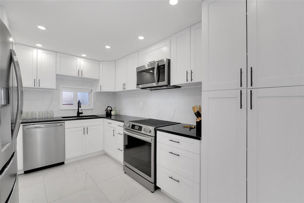 8911 South Hollybrook Boulevard, Unit 201 Pembroke Pines, FL 33025 - Photo 5 of 31 a kitchen with stainless steel appliances granite countertop white cabinets a sink a stove a microwave and a refrigerator