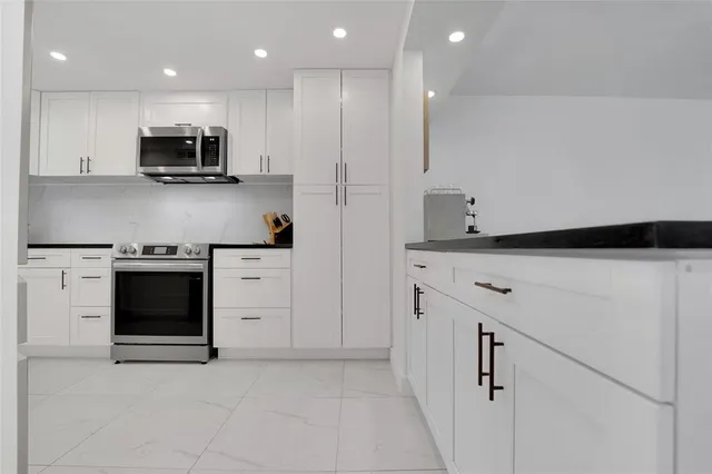 a kitchen with granite countertop white cabinets and stainless steel appliances