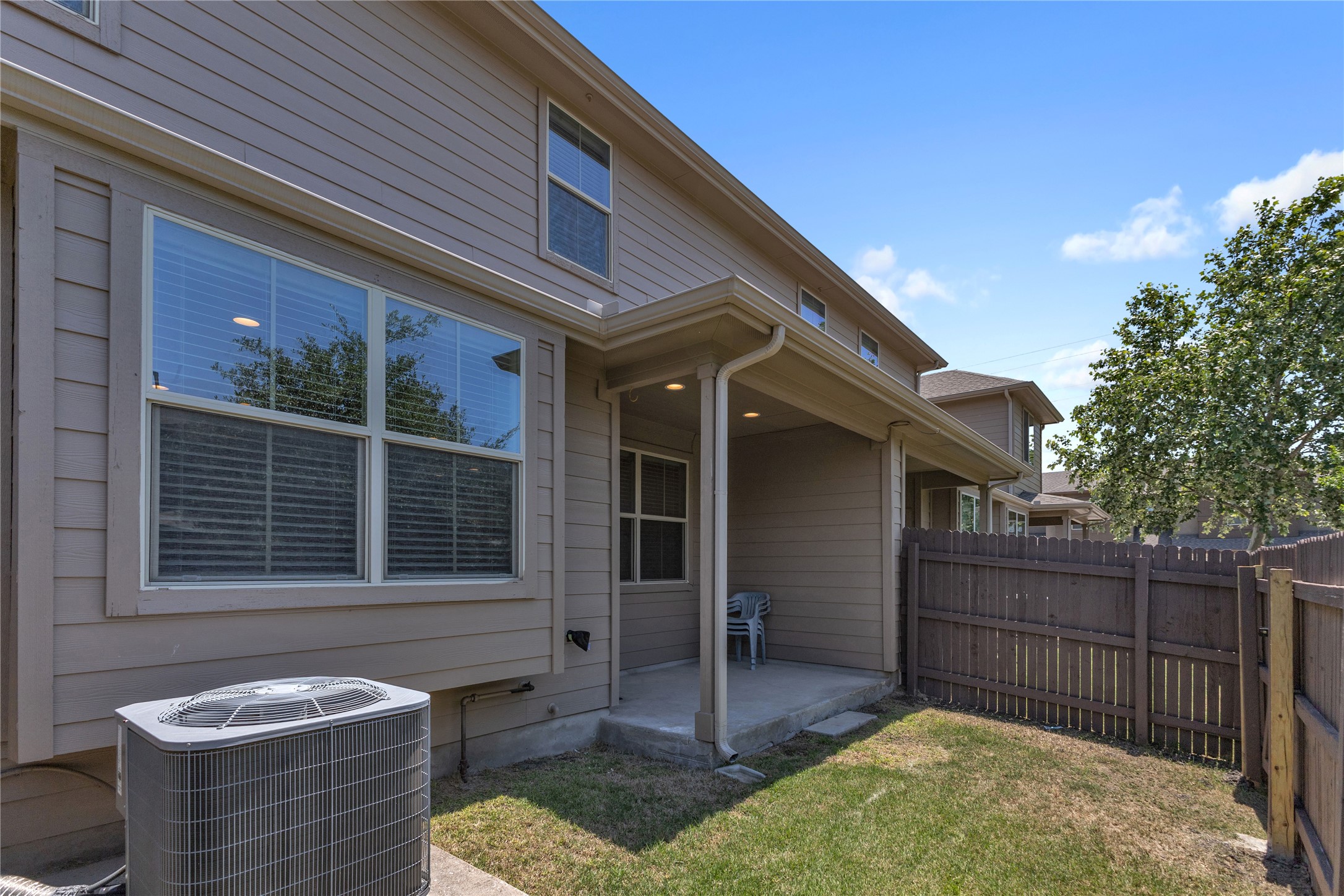 2880 Donnell Drive, Unit 2003 Round Rock, TX 78664 - Photo 30 of 31 Rear exterior featuring tan siding, a covered concrete patio, and a fenced yard