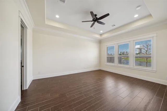 a view of empty room with wooden floor and fan