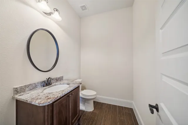 a bathroom with a granite countertop sink toilet and a mirror