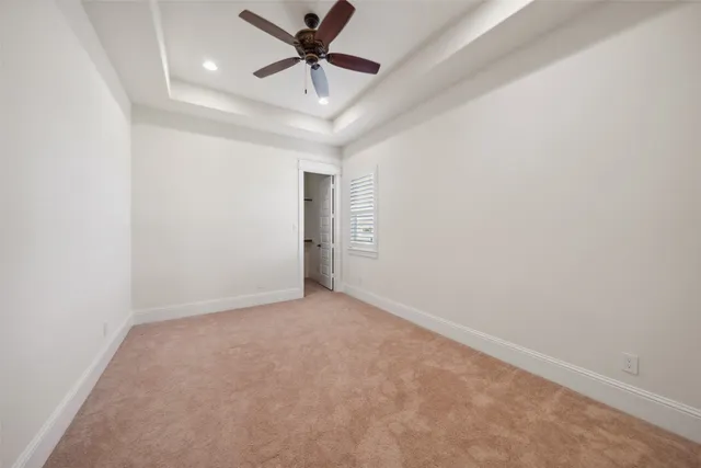an empty room with a chandelier fan and windows