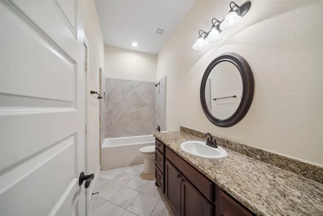 a bathroom with a granite countertop sink a mirror and a bathtub