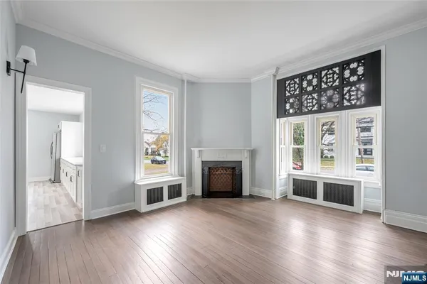 an empty room with wooden floor a fireplace and windows