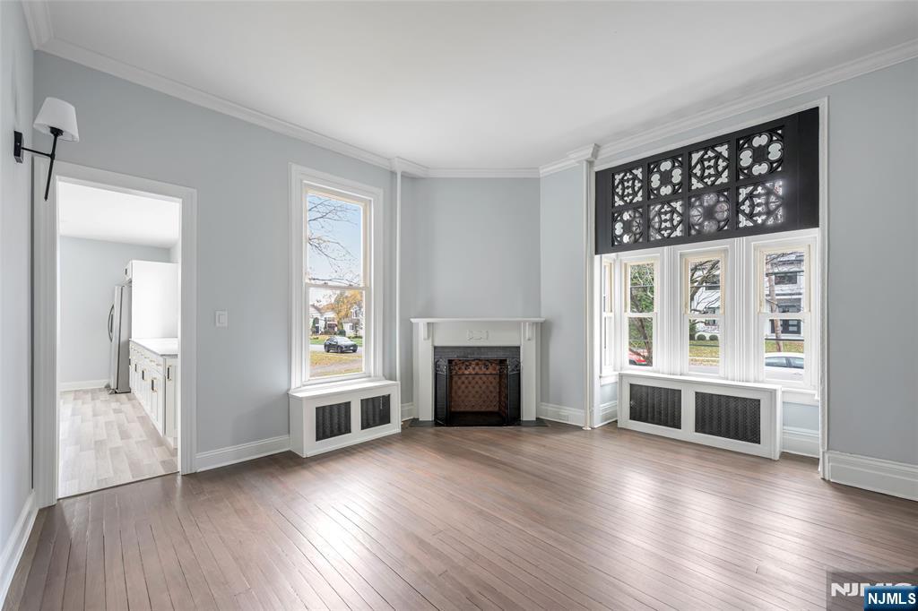 684 Closter Dock Road Closter, NJ 07624 - Photo 11 of 30 an empty room with wooden floor a fireplace and windows