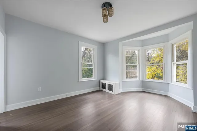 an empty room with wooden floor fireplace and windows