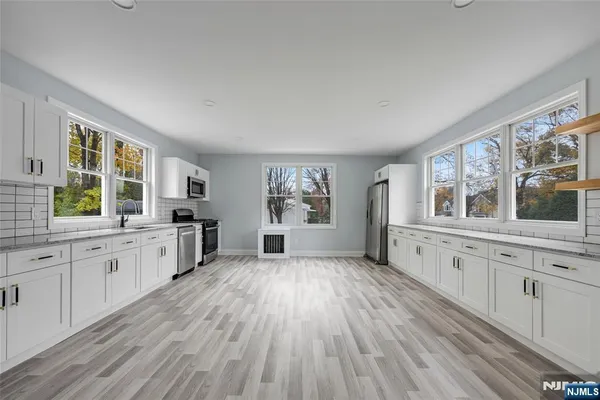 a large kitchen with a lot of window and wooden floor