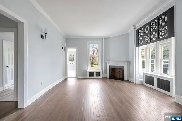 an empty room with wooden floor a fireplace and windows