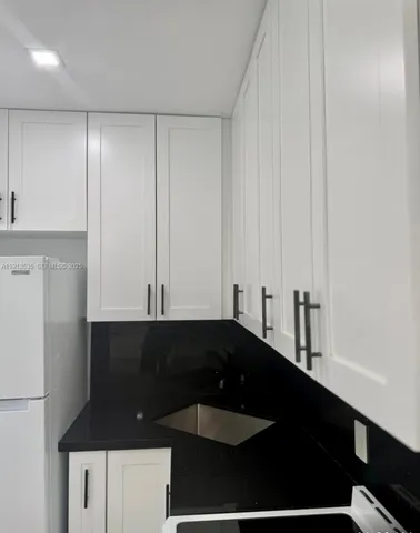 a kitchen with granite countertop white cabinets and black appliances