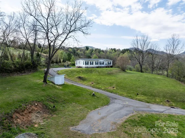 a view of a house with big yard and large trees