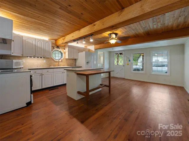 a kitchen with granite countertop a stove a sink and white cabinets with wooden floor next to windows
