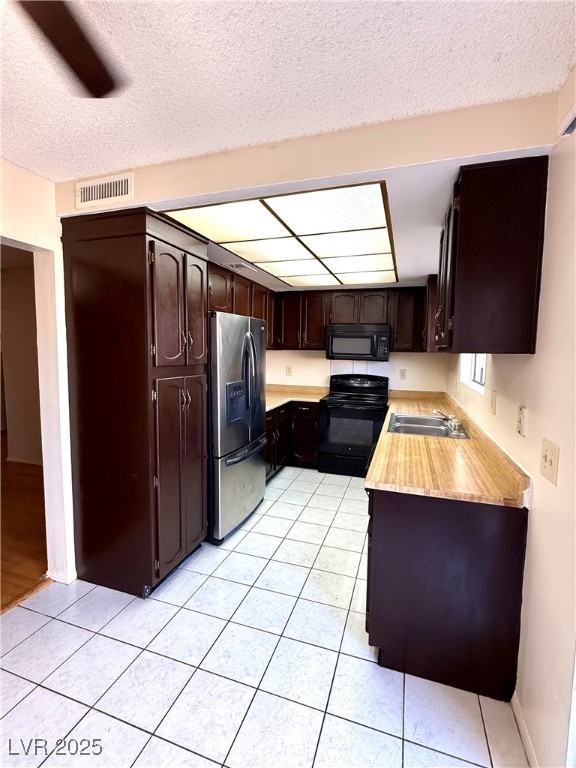 3367 Reka Street Las Vegas, NV 89121 - Photo 2 of 38 Kitchen featuring dark brown cabinets, light countertops, black appliances, a textured ceiling, and light tile patterned floors