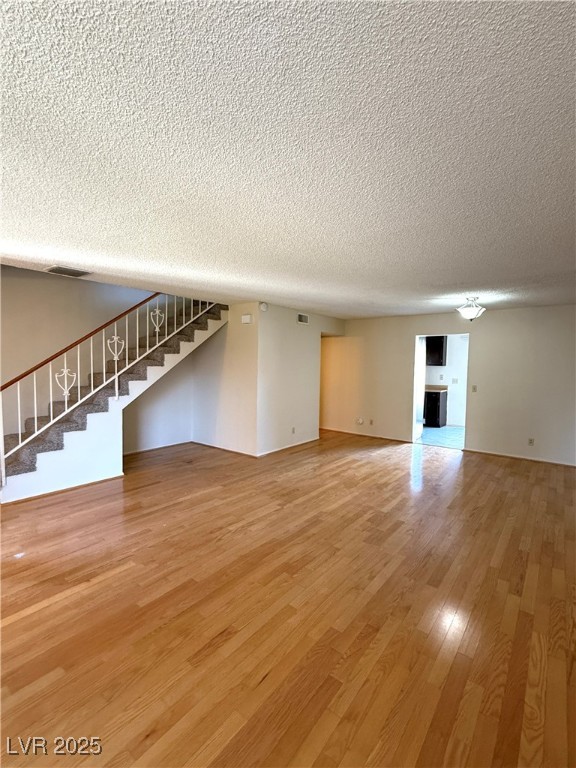 3367 Reka Street Las Vegas, NV 89121 - Photo 5 of 38 Unfurnished living room with stairway, light wood-type flooring, and a textured ceiling