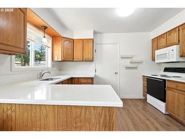 a kitchen with stainless steel appliances a sink a stove a refrigerator cabinets and wooden floor