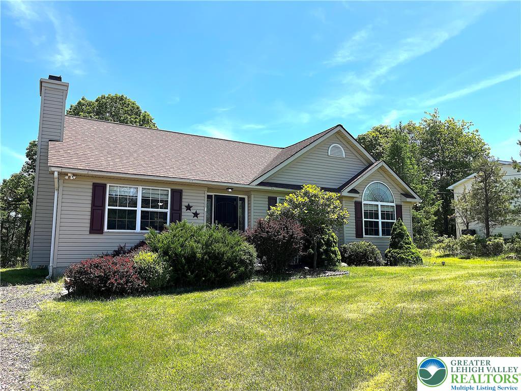 1646 Clover Road Long Pond, PA 18334 - Photo 2 of 24 Manicured landscaping surrounds this charming single-story home beneath a clear blue sky.