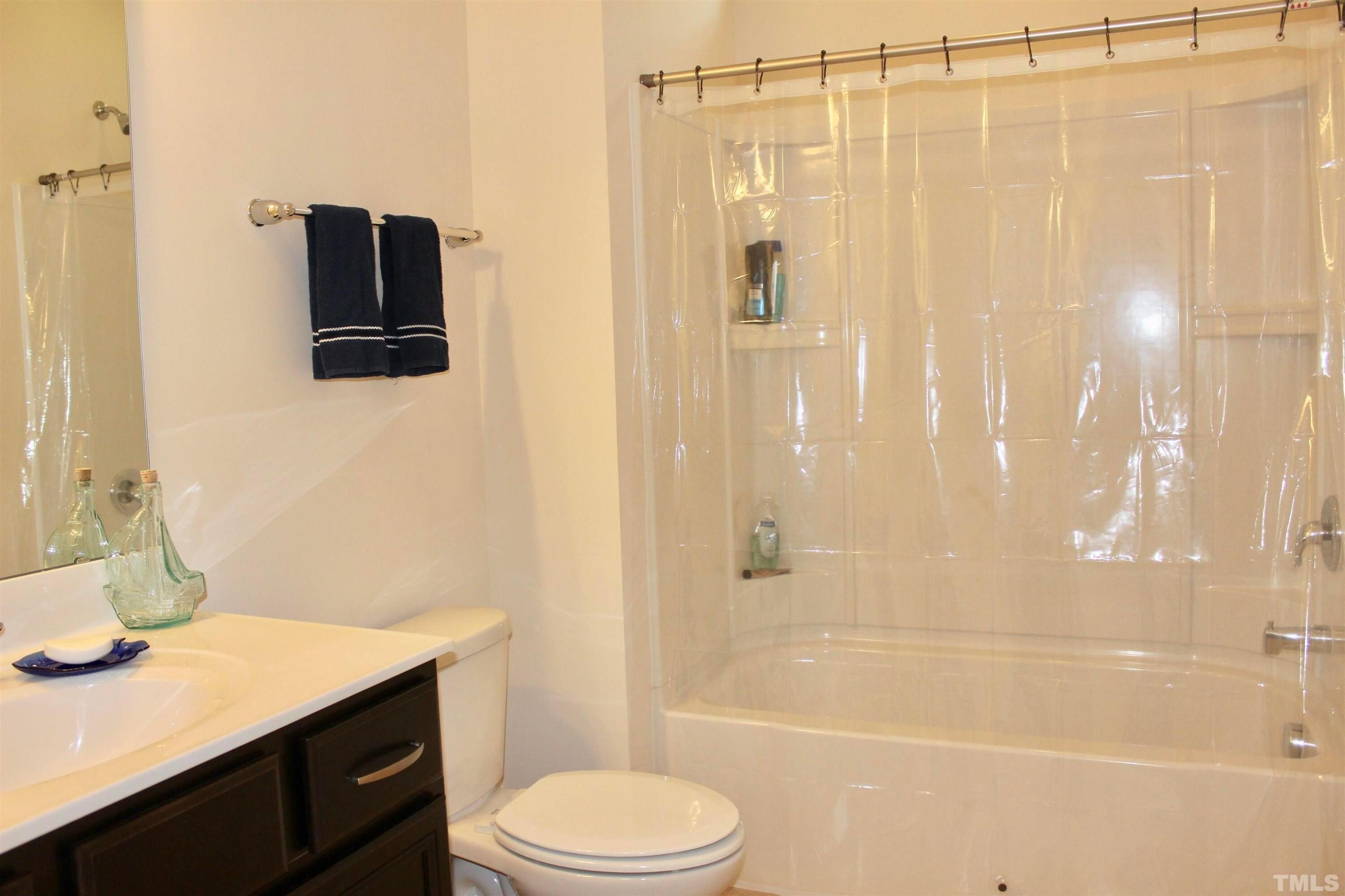 1608 Topaz Lane Apex, NC 27502 - Photo 17 of 23 a bathroom with a sink a toilet a mirror and shower