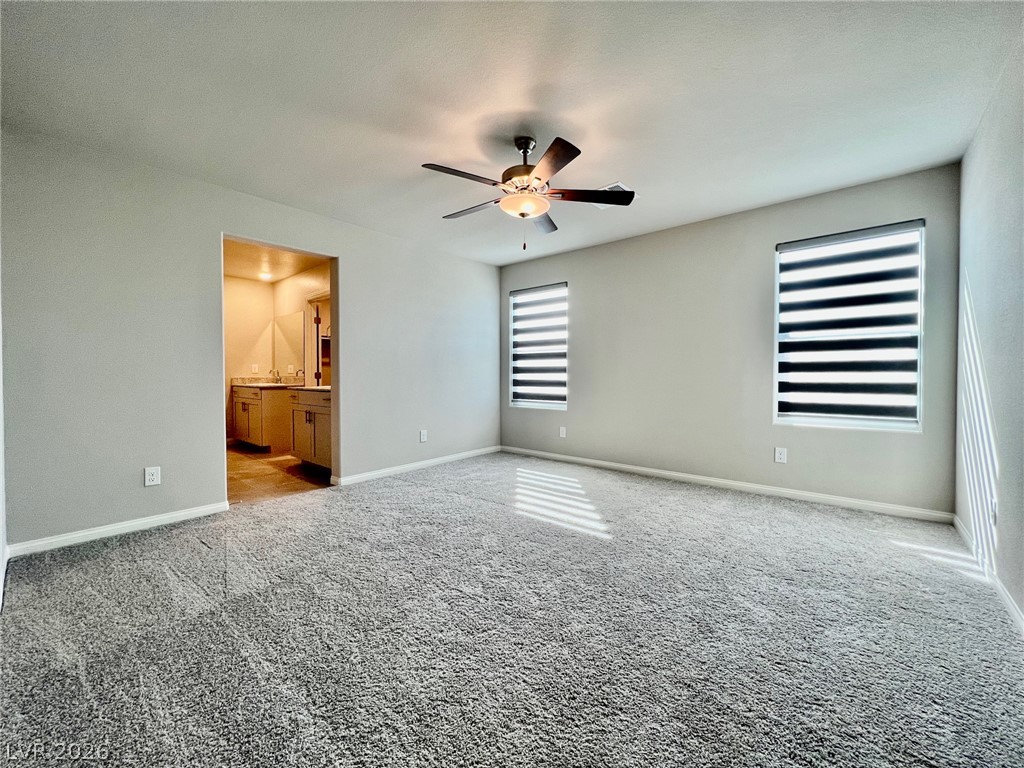 7845 Morganite Avenue Las Vegas, NV 89113 - Photo 15 of 21 A spacious primary bedroom with a ceiling fan, plush carpeting, and direct access to an attached bathroom.