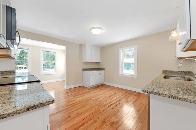 a view of a kitchen with granite countertop sink and dishwasher a refrigerator with wooden floor