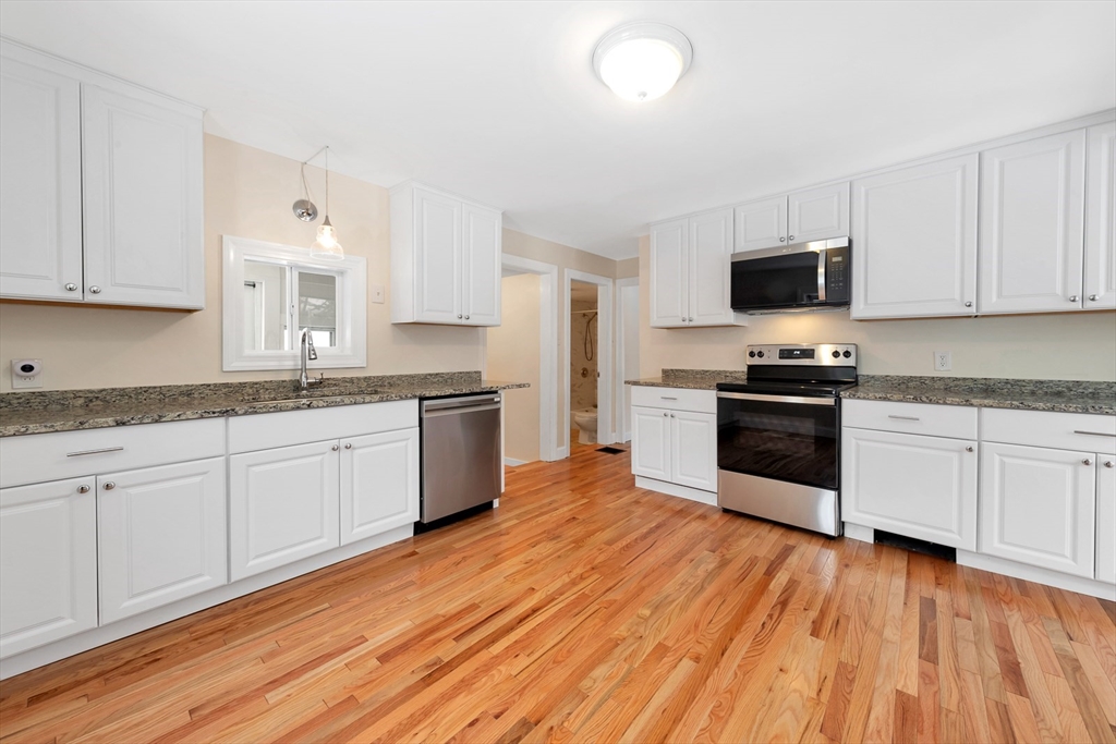 92 Squannacook Road Shirley, MA 01464 - Photo 14 of 22 a kitchen with granite countertop a stove top oven a sink dishwasher and a refrigerator with wooden floor