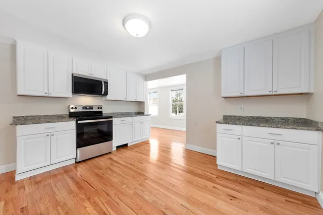 a kitchen with granite countertop a stove top oven a sink and white cabinets