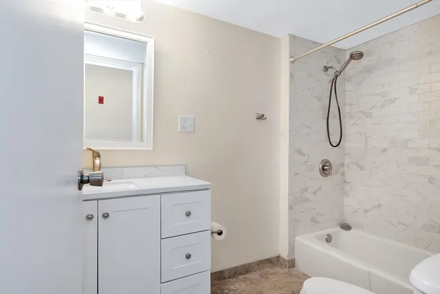 a bathroom with a granite countertop sink a toilet and shower