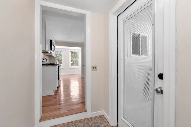 a view of a hallway with wooden floor and a livingroom