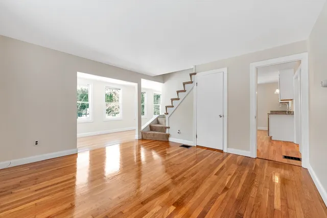 a view of empty room with wooden floor and stairs