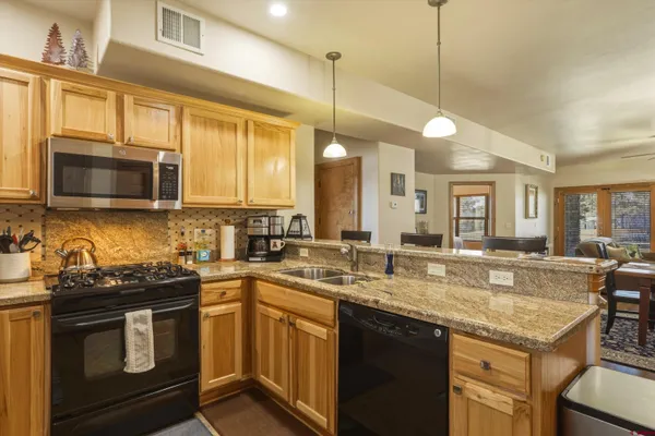 a kitchen with stainless steel appliances granite countertop a refrigerator stove and sink