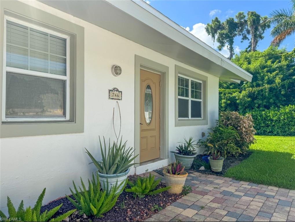 746 109th Avenue North Naples, FL 34108 - Photo 1 of 22 a potted plant sitting in front of a house with a garden