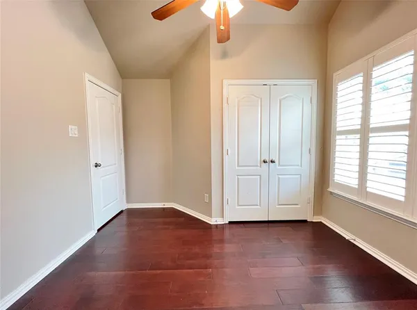 an empty room with wooden floor chandelier fan and windows