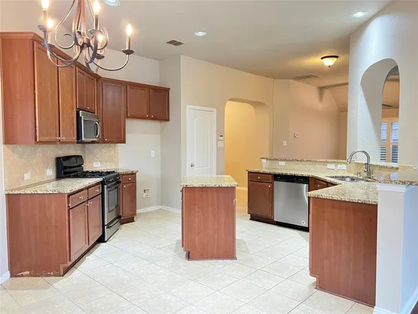 a large kitchen with a large counter top space a sink stainless steel appliances and cabinets