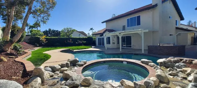 a view of a house with backyard swimming pool and furniture