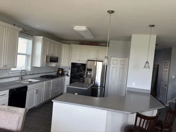 a kitchen with stainless steel appliances granite countertop a refrigerator a sink a stove a dining table and chairs