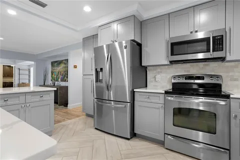 a kitchen with cabinets stainless steel appliances and wooden floor