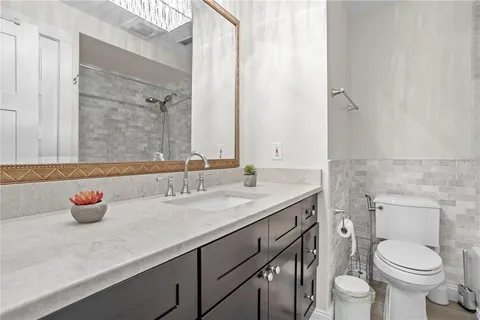 a bathroom with a granite countertop toilet a sink and a mirror