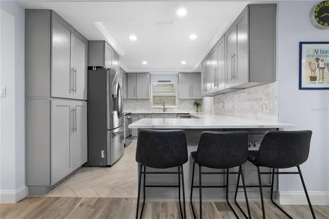 a kitchen with stainless steel appliances granite countertop a refrigerator a sink a stove a dining table and chairs