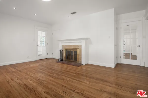 a view of empty room with wooden floor and fireplace
