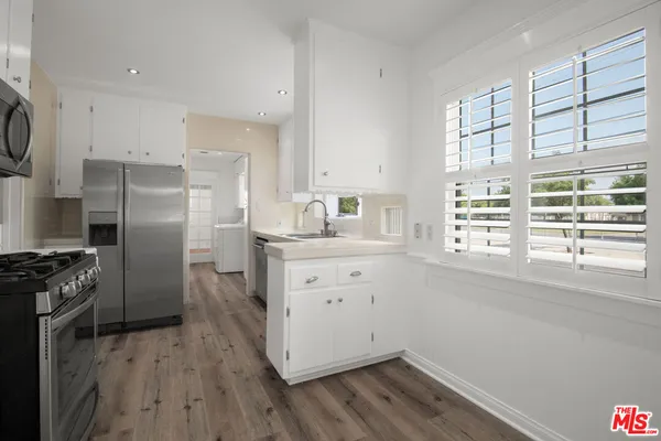 a kitchen with a refrigerator stove and wooden floor