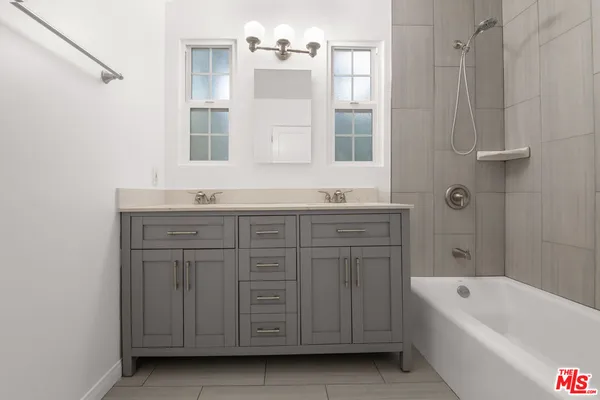 a bathroom with a tub a double vanity sink and mirror