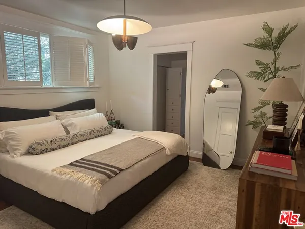 a bedroom with a bed a mirror and dresser