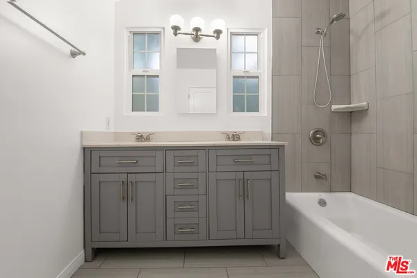 a bathroom with a tub a double vanity sink and mirror