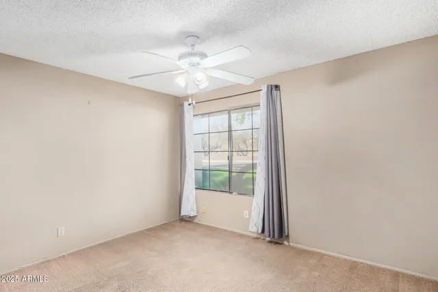 an empty room with a window and a fan