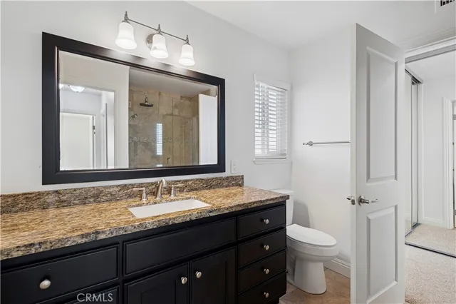 a bathroom with a granite countertop sink toilet and mirror