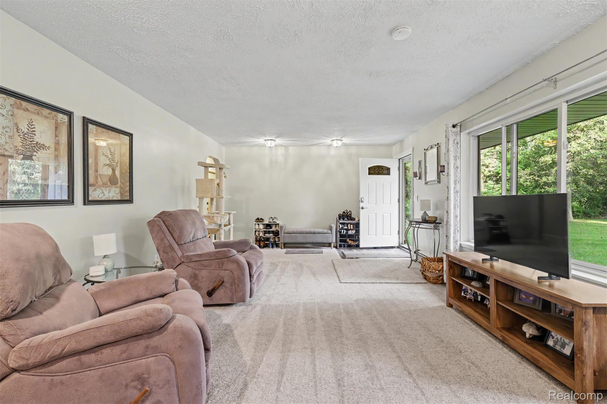 45223 Wear Road Belleville, MI 48111 - Photo 11 of 60 Expansive room with neutral carpeting, large sliding glass doors, white entry door with an arched window, and recessed lighting