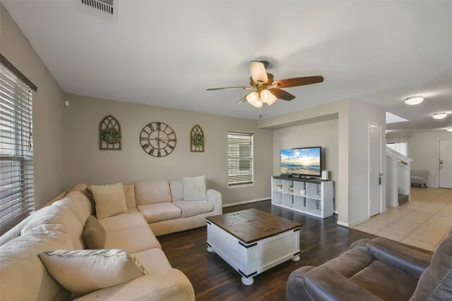 a living room with furniture a flat screen tv and a ceiling fan