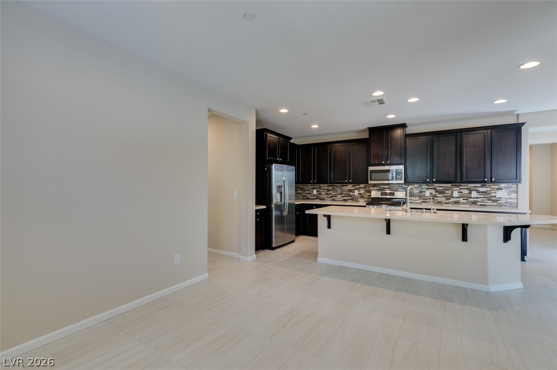 2549 Sable Ridge Street Henderson, NV 89044 - Photo 21 of 48 A contemporary kitchen features dark cabinetry, stainless steel appliances, and a central island with sleek countertops.