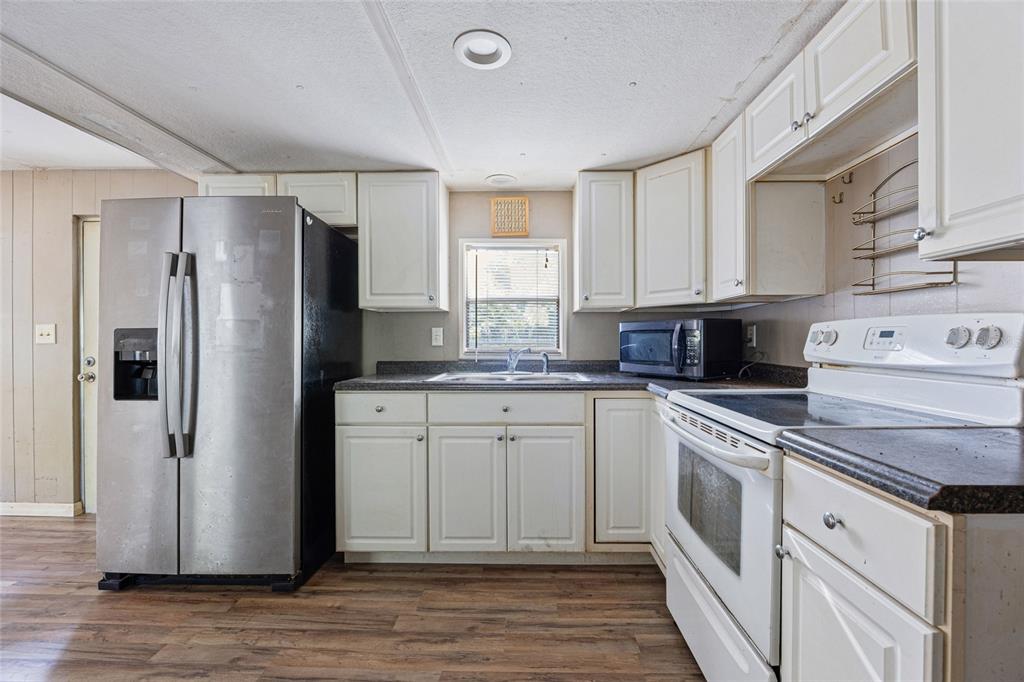 2780 County Road 575 Bushnell, FL 33513 - Photo 11 of 57 a kitchen with white cabinets stainless steel appliances and a window