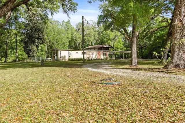 an aerial view of residential house with outdoor space and trees all around